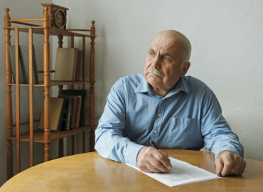 un hombre mayor escribe en un papel