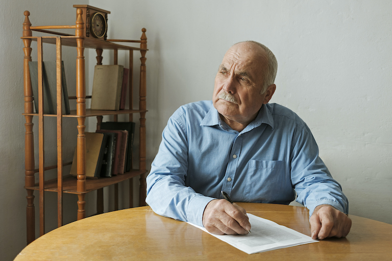 un hombre mayor escribe en un papel